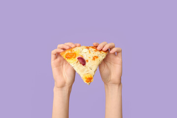 Female hands holding tasty pizza slice on lilac background