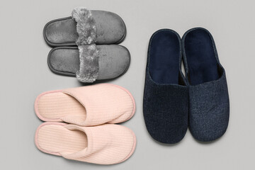 Three pairs of slippers on grey background. Top view