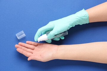 Woman applying sanitizer on her hands against blue background
