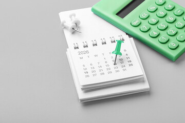 Calendar with green pin on date, closeup with calculator