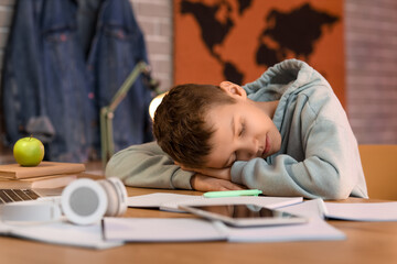 Teenage boy sleeping on table with notebooks in room