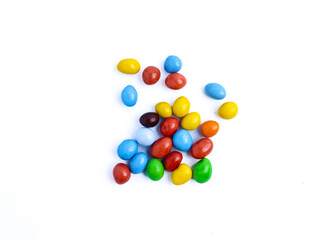 Colorful candy-coated chocolate pieces scattered on a white background