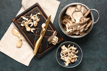 Board and colander with fresh oyster mushrooms on blue background