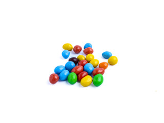 Colorful candy-coated chocolate pieces scattered on a white background