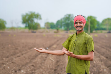 young indian farmer standing at agricultural field