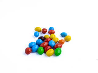 Colorful candy-coated chocolate pieces scattered on a white background