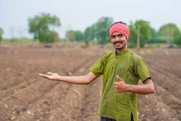 young indian farmer standing at agricultural field
