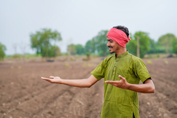 young indian farmer standing at agricultural field