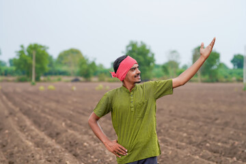 young indian farmer standing at agricultural field
