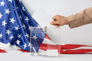 Voting man near ballot box on table and flag of USA against white background
