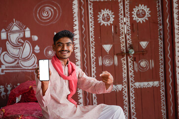young indian farmer showing smartphone screen