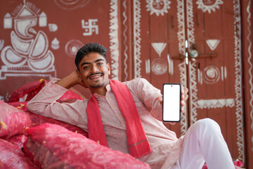 young indian farmer showing smartphone screen