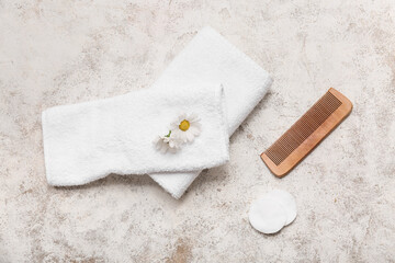 Beautiful composition with clean soft towels, wooden comb, cotton pads and cotton flower on grunge background