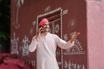 young indian farmer talking on smartphone at home