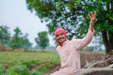 young indian farmer standing at green agricultural field