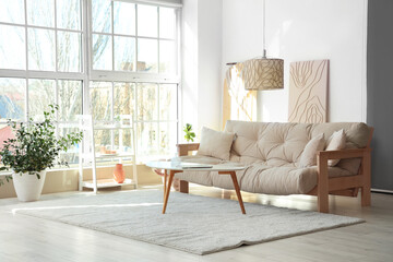Light interior of modern living room with comfy sofa, coffee table and lamp