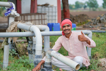young indian farmer sitting at agricultural field