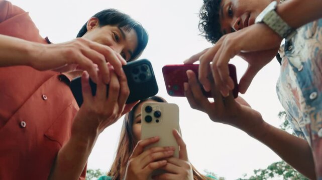 Close-up of multiple hands using smartphones during a casual outdoor interaction. Digital teamwork among youth using mobile phones for communication and collaboration.