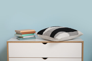 Chest of drawers with books and pillow in room