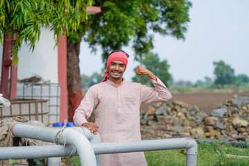young indian farmer standing at agricultural field