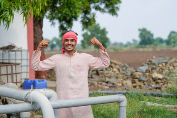 young indian farmer standing at agricultural field