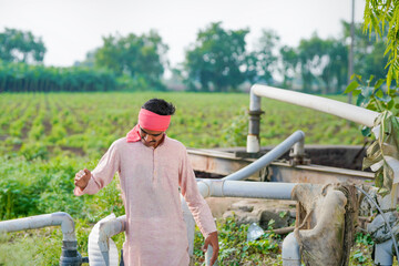 young indian farmer standing at agricultural field