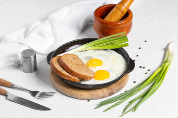 Composition with tasty fried eggs, spices and green onion on light background