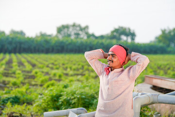 young indian farmer standing at green agricultural field