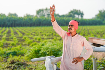 young indian farmer standing at green agricultural field