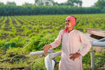 young indian farmer standing at green agricultural field
