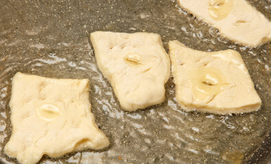 Three pieces of food are frying in a pan