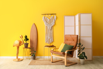 Interior of beautiful living room with surfboard, armchair, coffee table and folding screen