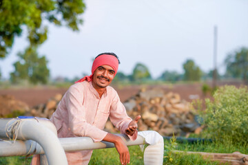 young indian farmer standing at agricultural field