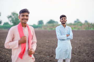 young indian farmer standing at agricultural field