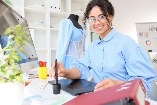 Female African-American graphic designer working with tablet at table in office - Powered by Adobe