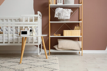 Baby monitor with toy bunny on table in children's bedroom interior
