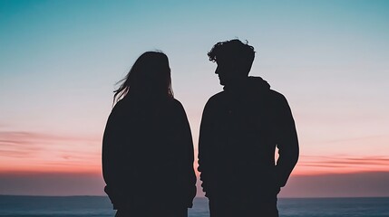 Silhouette romance: a young couple contemplates the horizon during a vibrant coastal sunset