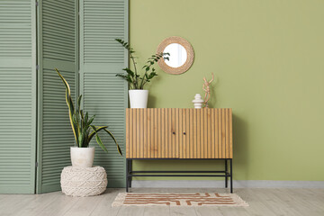 Interior of living room with mirror, commode and green folding screen