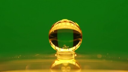 Golden liquid droplet impact sequence on surface in slow motion and green background - Powered by Adobe