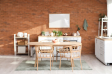 Blurred view of kitchen with dining table, shelf units and plants