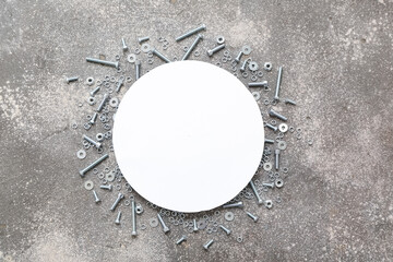 Blank greeting card with different tap bolts and chrome nuts on grey grunge background