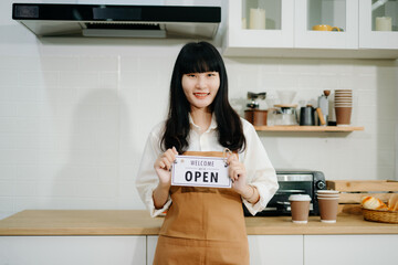 Young Asian woman coffee shop owner holding notepad and digital tablet ready to receive orders in cafe restaurant.