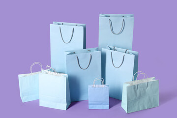Many blue shopping bags on lilac background