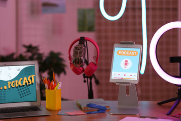 Podcaster's workplace with microphone and glowing neon lamp in dark studio, closeup