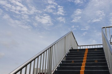 Obraz premium Staircase and railing of overhead crosswalk, clouds blue sky background 