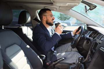 Handsome young man with cup of coffee driving a car. I love my car concept