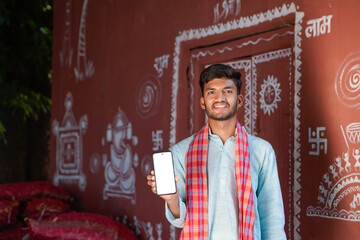 young indian farmer showing smartphone screen