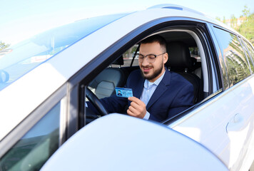 Handsome young man with driving license in car. I love my car concept