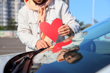 Young man putting heart on windshield, closeup. I love my car concept