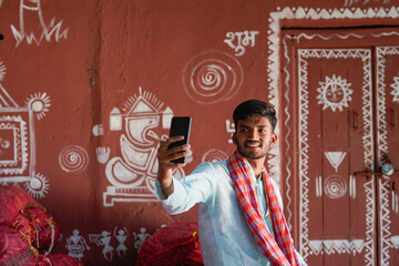 young indian farmer using smartphone at home